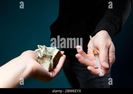 Hand hält zerknitterte Dollar im Austausch für eine Spritze mit einer Dosis von Medikamenten, Nahaufnahme Stockfoto