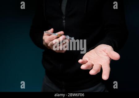 Der Mann hält eine Spritze mit einem Medikament und hält seine leere Hand, deutet auf eine Zahlung für das Medikament, selektive Fokussierung Stockfoto