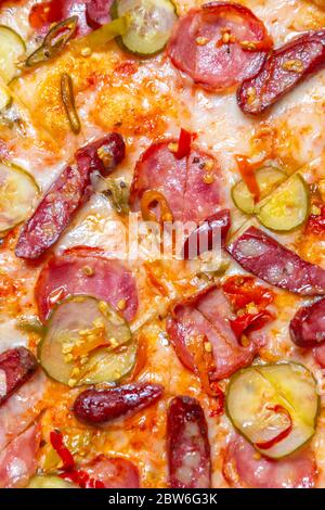 Italienische Pizza im Ofen gebacken mit geräucherten Würstchen, Gurken eingelegter, Mozzarella Käse und Pilzen.Delicious Fast Food für Abendessen.Hintergrund für Pizzerien Stockfoto