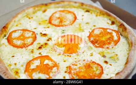 Vier Käse Pizza mit geschnittenen Tomaten im Ofen für die Lieferung gebacken.Fast Food Restaurant Gericht in Karton geliefert.Italienische traditionelle Küche me Stockfoto