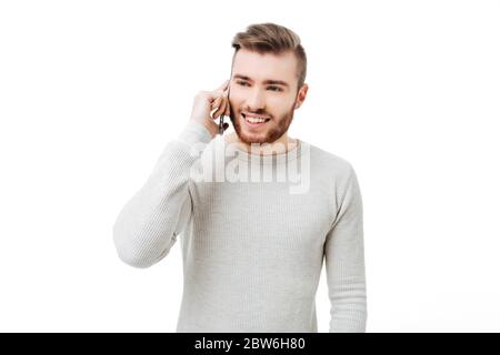 Fröhlicher junger Mann, der isoliert am Telefon telefoniert Stockfoto
