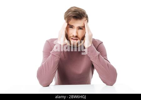 Junger Mann zeigt Kopfschmerzen Geste sitzen an dem Tisch isoliert Stockfoto