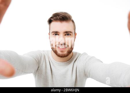 Junge attraktive Mann unter Selfie auf weißem Hintergrund. Ansicht der Frontkamera Stockfoto