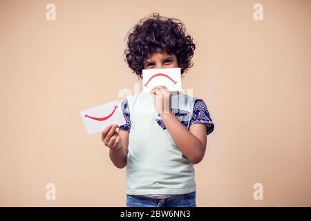 Ein Porträt des Jungen, der Karten mit positiven und negativen Symbol hält. Kinder und Emotionen Konzept Stockfoto