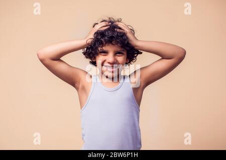 Ein Porträt von lächelndem Jungen mit lockigen Haaren. Kinder und Emotionen Konzept Stockfoto