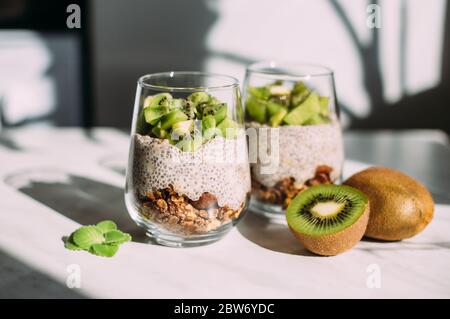 Gesundes Frühstück. chia Pudding mit Kiwi und Müsli in Glas auf weißem Hintergrund Stockfoto