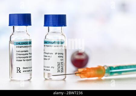 Chloroquinphosphat (generischer Name) Medikament in kleinen Injektionsflaschen mit blauen Kappen, orange grüne Spritze in der Nähe (eigenes Label Design mit Dummy-Daten - nicht Stockfoto