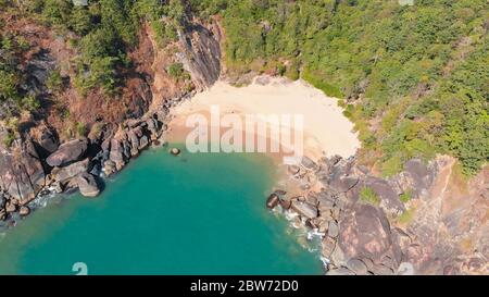 Schöner geheimer Strand Butterfly in Goa, Indien. Luftaufnahme des unberührten Strandes mit felsigen Bucht und Wellen, die zusammenbrechen. Stockfoto