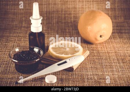 Behandlung von Erkältungen und Grippe. Verschiedene Medikamente, Thermometer, kalte Pillen, Kehlspray, Nasentropfen, Zitrone auf braunem Hintergrund. Behandlung von Einfluss Stockfoto