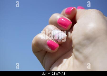 Frauenhand zeigt ihre halbpermanente Maniküre. Rosa Stockfoto