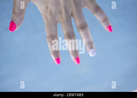 Frauenhand zeigt ihre halbpermanente Maniküre. Rosa Stockfoto