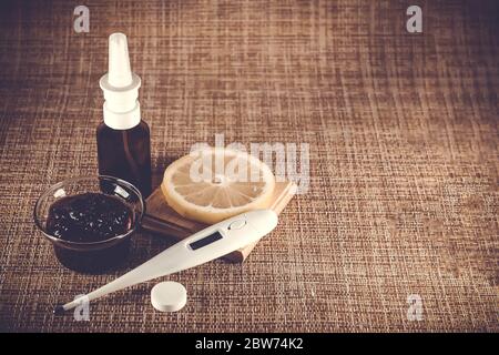 Behandlung von Erkältungen und Grippe. Verschiedene Medikamente, Thermometer, kalte Pillen, Kehlspray, Nasentropfen, Zitrone auf braunem Hintergrund. Behandlung von Einfluss Stockfoto