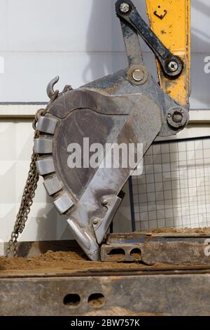 Nahaufnahme des Baggers (Grader, Traktor) Schaufel mit Ketten auf der Baustelle Stockfoto