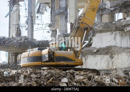 Nahaufnahme von speziellen hydraulischen Bagger-Zerstörer während des Betriebs, Ruinen eines Gebäudes auf dem Hintergrund. Extrem hohe Abbruchausrüstung Stockfoto