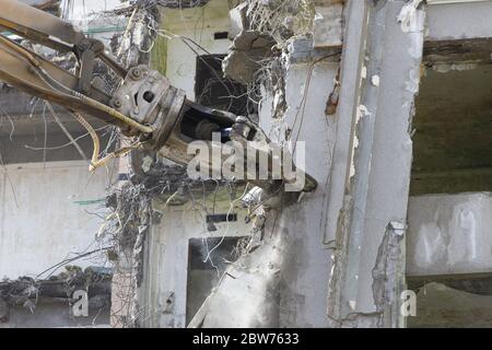 Abriss des Gebäudes. Kran mit hydraulischer Schere Nahaufnahme greifen. Stahlbetonkonstruktionen. Stockfoto