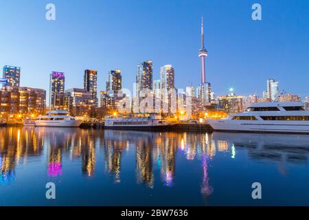 TORONTO, KANADA - 16. APRIL 2015: Blick auf die Innenstadt von Toronto bei Dämmerung mit Gebäuden, Eigentumswohnungen, dem CN Tower und Booten. Stockfoto