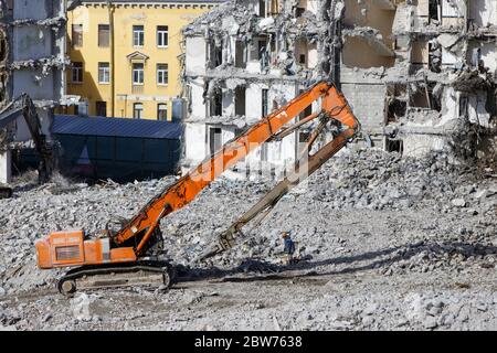 Abriss des Gebäudes mit Bagger-Zerstörer für Höhenarbeit. Kran mit Hydraulikschere greifen. Stahlbetonkonstruktionen. Stockfoto