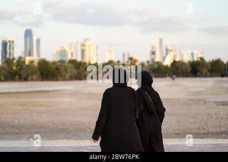 Bahrain Stadt / Bahrain - 15. Januar 2020: Muslimische Frauen tragen Balck Abaya Niqab zu Fuß in der Nähe der touristischen Qal'at al-Bahrain während Sonnenuntergang Zeit Stockfoto