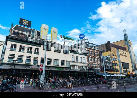 Amsterdam, Niederlande - 9. September 2018: Straße mit Menschen auf den Terrassen der Bar und Heineken Schild in Amsterdam, Niederlande Stockfoto