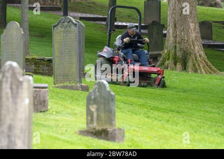 Saint John, New Brunswick, Kanada - 25. Juli 2018: Ein Mann, der einen Rasenmäher benutzt, um den Rasen in einem Grabhof zu mähen. Stockfoto