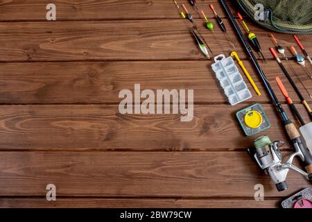 Angelausrüstung - Angelrute Angelrute und Zubehör auf Holzhintergrund, Kopierraum. Stockfoto