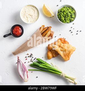 Gebratener Fisch und Chips in einem Papierkegel auf weißem Hintergrund mit allen Komponenten klassisches Rezept Take Away Food Draufsicht weißer Stein strukturierter Hintergrund aufhört Stockfoto