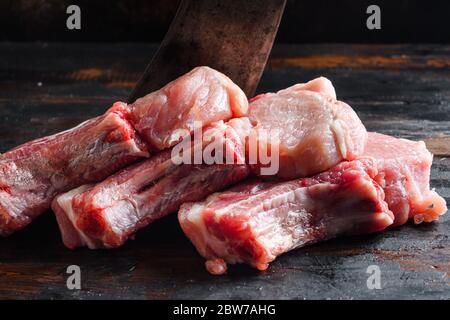 Frisches rohes Schweinefleisch aus Bio-Bauernhof über rustikalen Holz und Metall Hintergrund Seitenansicht close up Stockfoto