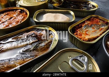 Konserven von Fisch aus der Dose mit verschiedenen Fischarten und Meeresfrüchten, offene und geschlossene Dosen mit Saury, Makrele, Sprossen, Sardinen, Sardinen, Sardellen, Tintenfisch, tun Stockfoto