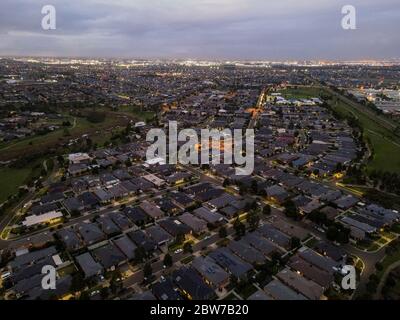 Luftaufnahme von neuen Häusern in neuen Vororten gebaut städtischen Zersiedelung Regierung Rabatte am Abend mit Parklandschaft und Lichter der Stadt Melbourne Victoria Australien Stockfoto