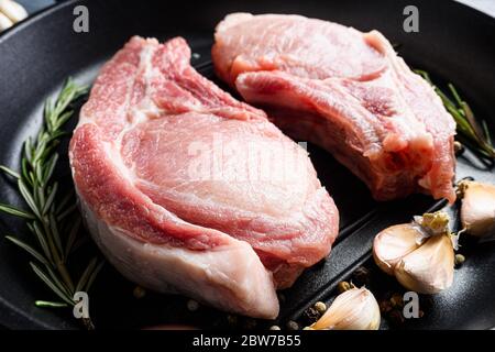 Rohes Gourmet-Schweineschnitzel für Grill in Bratpfanne schwarze Pfanne mit Kräutern, Gewürze aus nächster Nähe. Stockfoto