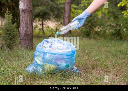 Müll aufnehmen und in einen Papierkorb legen Stockfoto