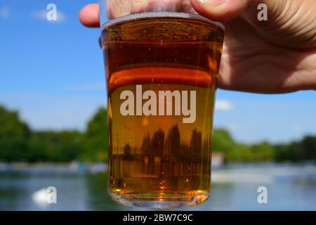 Eine Frauenhand mit einem Glas Bier im Hyde Park, London Stockfoto
