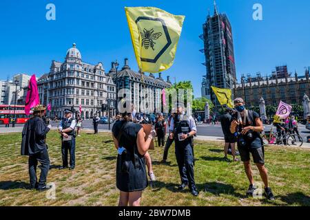 Einer Mutter und ihrem 3-jährigen wird eine Geldstrafe drohen, aber nach einer langen Diskussion, ziehen Sie weiter - sobald sie ankommen, zieht die Polizei ein und beginnt, erste Geldstrafen zu drohen und dann festzunehmen (auf der Grundlage, dass es sich um eine illegalrechtliche Lockdown-Versammlung handelt, Auch wenn sie alle über 2m auseinander liegen), wenn sie nicht gehen - Aussterben Rebellion eine Stunde lang auf dem Parliament Square schweigt, sozial distanziert protestiert. Sie wollen ihre Unzufriedenheit mit "Inkompetenz der Regierung und fordern eine Bürgerversammlung zur Erholung des Covid-19" zum Ausdruck bringen, da sie glauben, "die politischen Institutionen sind nicht in der Lage o Stockfoto