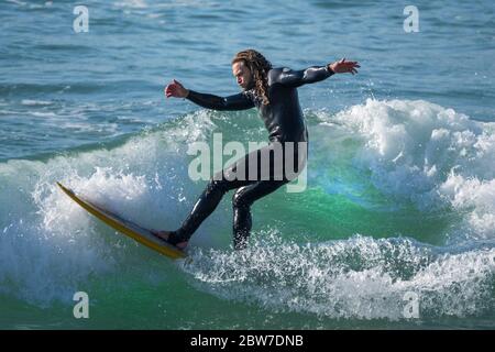 Spektakuläre Action als männlicher Surfer auf einer Welle im Fistral in Newquay in Cornwall reitet. Stockfoto