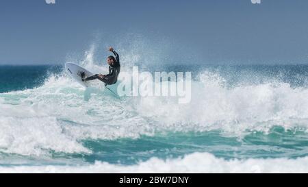 Ein Panoramabild von spektakulärer Action, während ein Surfer eine Welle bei Fistral in Newquay in Cornwall reitet. Stockfoto