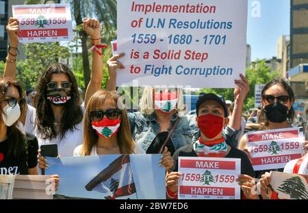 Beirut, Libanon. Mai 2020. Regierungsfeindliche Demonstranten, die Gesichtsmasken tragen, rufen Parolen und halten Plakate während eines Protestes, der die Umsetzung verschiedener Resolutionen des UN-Sicherheitsrates fordert, einschließlich der Abrüstung bewaffneter Gruppen im Land. Quelle: Marwan Naamani/dpa/Alamy Live News Stockfoto