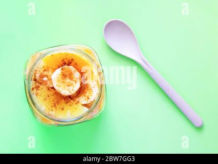 In Scheiben geschnittene Früchte mit Zimt in einem Glas und einem Löffel aus biologisch abbaubarem Kunststoff, bestehend aus natürlichen Fasern von Weizen, Stärke bestreut Stockfoto