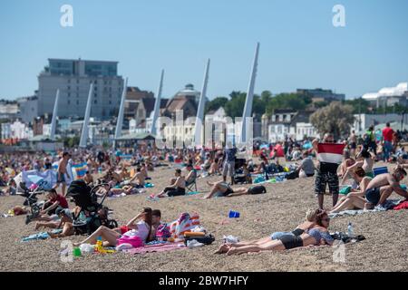 Menschen, die das gute Wetter am Strand von Southend-on-Sea in Essex genießen, werden daran erinnert, dass die Öffentlichkeit nach der Lockdown-Restriktionen soziale Distanzierungen praktiziert. Stockfoto