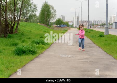 4 Jahre kleine Mädchen Spaß läuft entlang der Straße Stockfoto