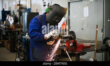 Arbeiter, der einen Winkelschleifer betreibt und viele Funken erzeugt Stockfoto