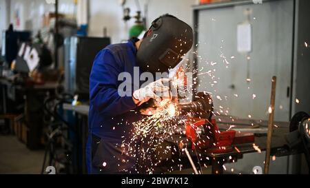 Arbeiter, der einen Winkelschleifer betreibt und viele Funken erzeugt Stockfoto