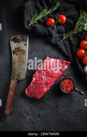 Roh, Flap oder Flanke, auch bekannt Bavette Steak in der Nähe Metzger Messer mit rosa Pfeffer und Rosmarin. Schwarzer Hintergrund. Draufsicht vertikal. Stockfoto