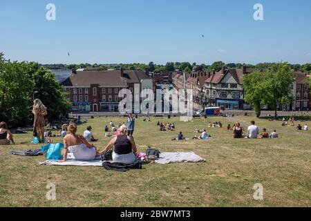 Blick auf die Menschen, die während der ersten Tage der Lockdown Lockdown-Lockdown-Lockerung während der COVID-19-Pandemie auf Windmill Hill mit Blick auf die Stadt Hitchin, Hertfordshire, sitzen Stockfoto