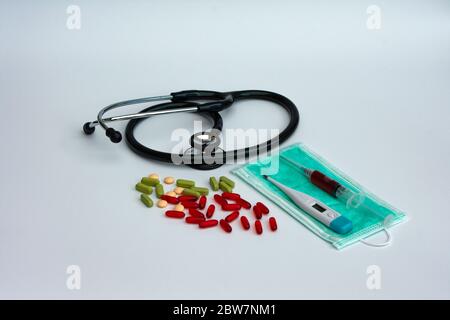 Behandlungskonzept für Coronavirus. Stethoskop, verschiedene Pillen, digitales Thermometer, chirurgische Maske und Blutprobe auf einer Spritze. Draufsicht. Stockfoto