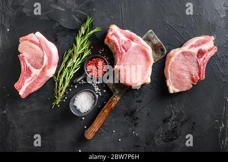 Bio-Schweinefleisch-Hackfleisch über amerikanischen klassischen Metzgermesser oder -Spalter mit Gewürzen und Rosmarin und rotem Pfeffer auf schwarzem Schiefer Tischansicht. Platz Stockfoto