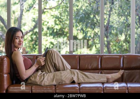 Asiatische Frau verbringen Ferien im Wohnzimmer. Die junge Frau überprüft E-Mails mit einem Tablet-Computer. Stockfoto