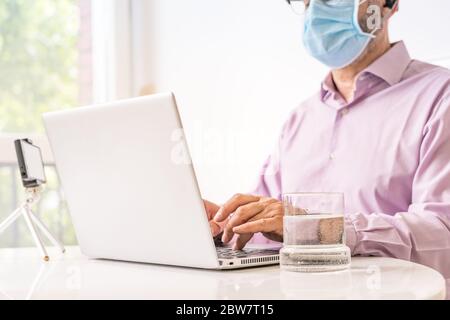 Mann, der mit Notebook und OP-Maske arbeitet. Stockfoto