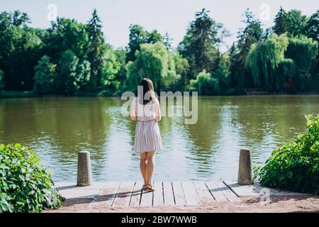 Sofia Park, Uman. Junge Frau mit einer touristischen Karte am See. Eine Frau in einem farbigen Kleid geht am Fluss entlang. Mädchen auf einem Hintergrund eines weißen Pavillons Stockfoto