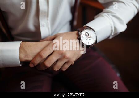 Herrenarmbanduhr, der Mann beobachtet die Zeit. Businessman-Uhr, Businessman überprüft die Zeit auf seiner Armbanduhr. Die Hände des Bräutigams in einem Anzug anpassen Stockfoto
