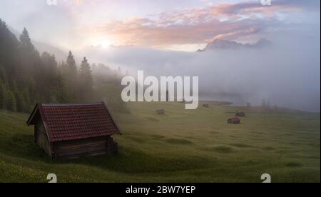 Perfekter Sonnenaufgang in den Bergen - Hütten, See, Nebel, buntes Himmel Stockfoto